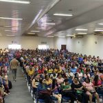 Imagem mostra um grupo de pessoas reunido em um ambiente de assembleia.