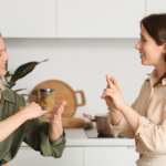 Duas mulheres, uma de frente para outra, fazem o uso de sinais.